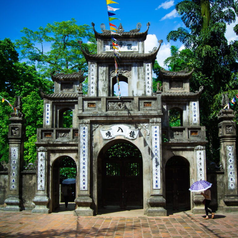 Girl walking with umbrella near Temple gates in Vietnam